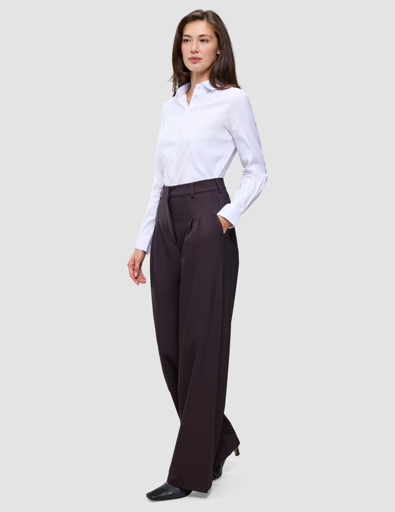 Eine Frau, die ein weißes Hemd trägt, das in die Damenhose Avira Pants Wide in der Farbe Burgundy Berry gesteckt ist.